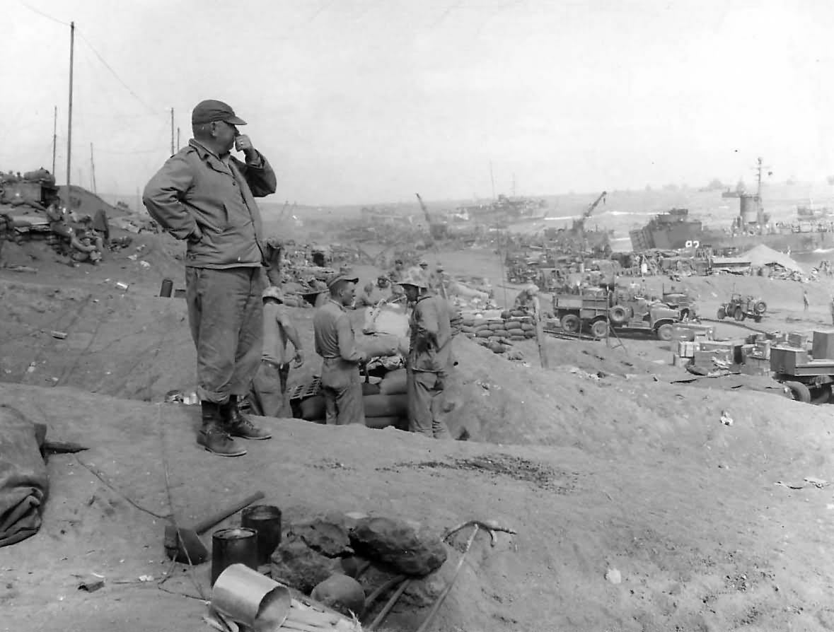 Capt. Carl Squeaky Anderson - Force Beach Master in charge of landing supplies on the beach of Iwo Jima, looks out over the beach as operations for the landing of supplies go ahead at full spe